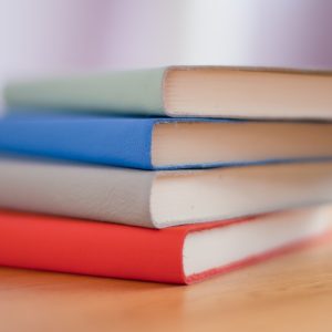 Stack of 4 books: green, blue, grey and red
