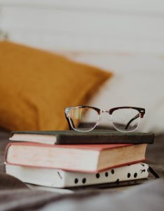 Reading glasses perched atop a stack of 3 books