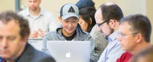 Person smiling and typing on a laptop at an event