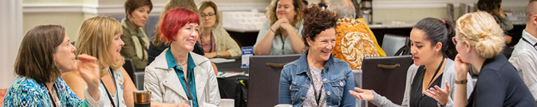 A diverse group of people of different ages and backgrounds smiling and enjoying themselves at a gaming event in Auckland