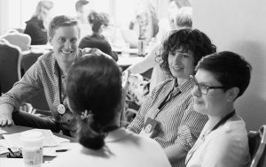 Black and white image of people chatting around a conference table