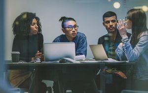4 young people collaborating with laptops