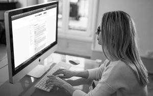 Side view, black and white image of person working on computer