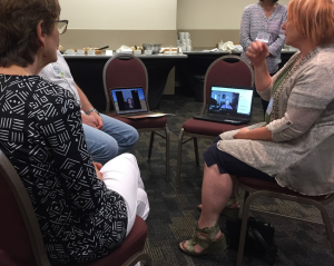 People sitting in a group, two chairs with laptops and attendees listening remotely