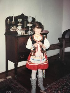 Seven-year-old Amanda wearing a traditional Polish costume and winter boots, and smiling at the camera