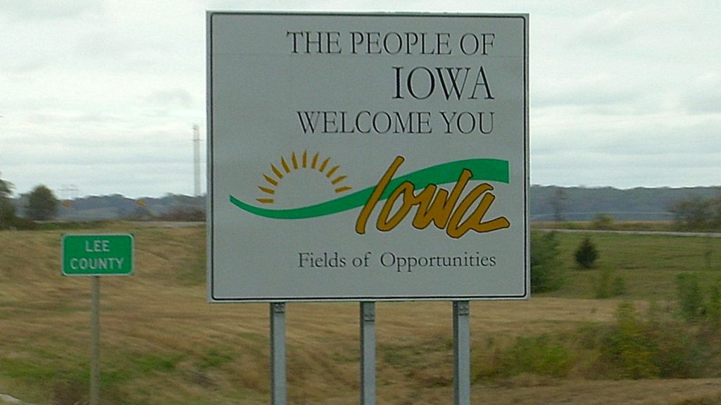 A "Welcome to IOWA" sign on the side of the highway