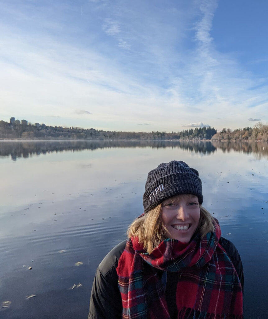 Nicola Mulberry smiling in front of a body of water and a blue sky