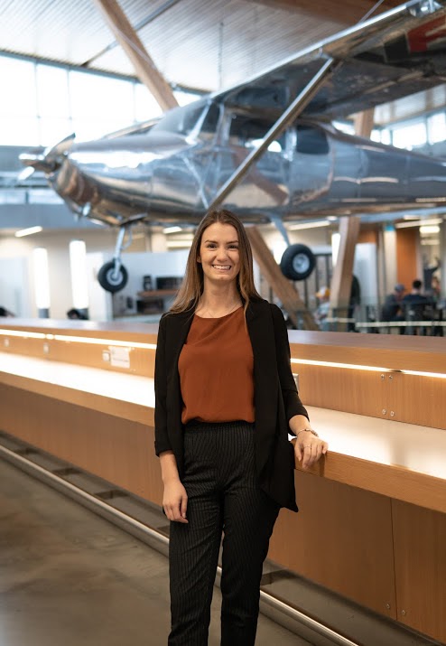 Saige Girouard stands in front of an airplane on display and suspended from the ceiling.