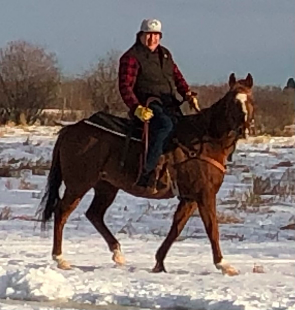 Josh Littlechild riding a horse in a snow covered field