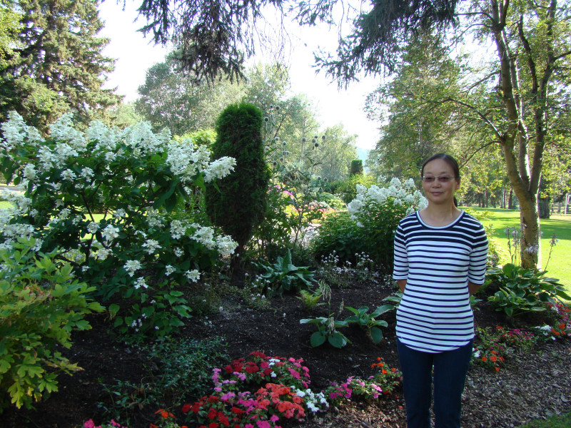 Photo of Mei standing in a garden in the sunshine. 