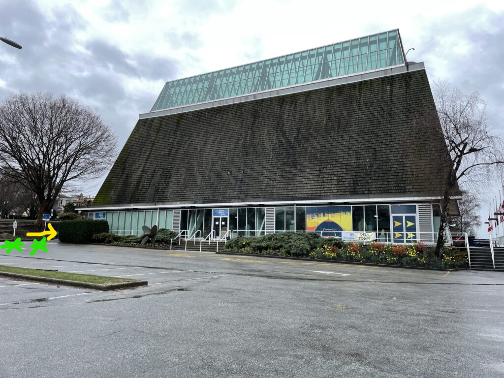 A building is shown with green stars marking the accessible parking spaces in front and a yellow arrow pointing in the direction of the ramp.