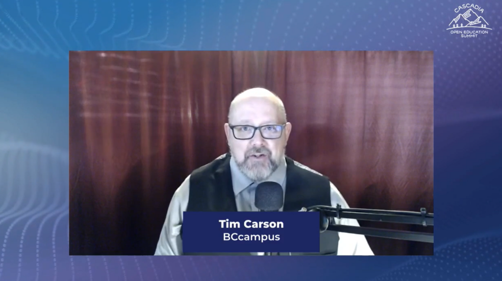 Screen capture of Tim Carson in vest and tie speaking into a microphone 
